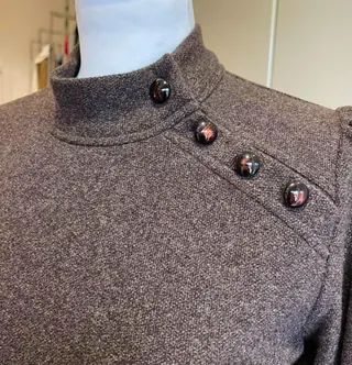 Collo alto di un abito in lana grigia con bottoni sullo scollo