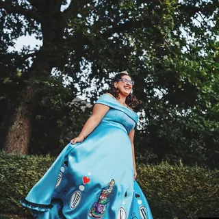 Ragazza in abito azzurro a tema Alice nel paese delle meraviglie in un parco
