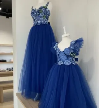 Due abiti in tulle blu con fiori applicati su manichini